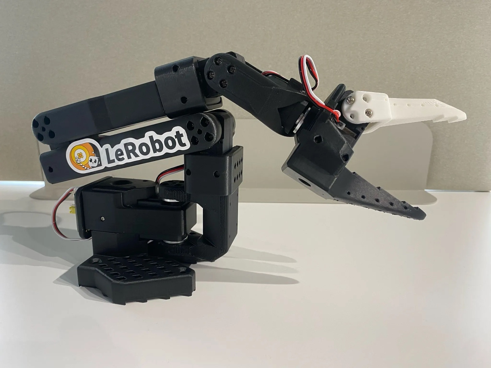 The real SO-101 open-source 3D-printed 6-DOF robot arm with a gripper on a desk